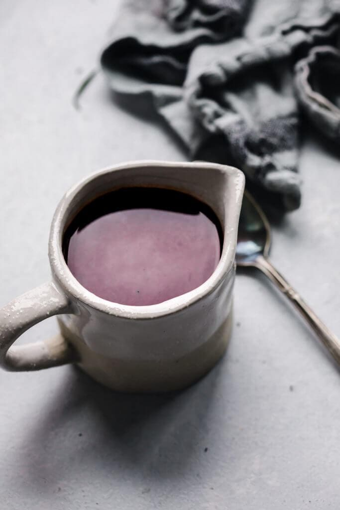 Red wine jus in small pouring vessel.