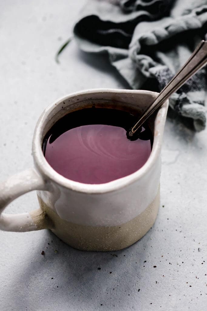 Red wine jus in small container with spoon. 