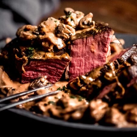 Side view of sous vide roast beef sliced and drizzled with creamy mushroom sauce.