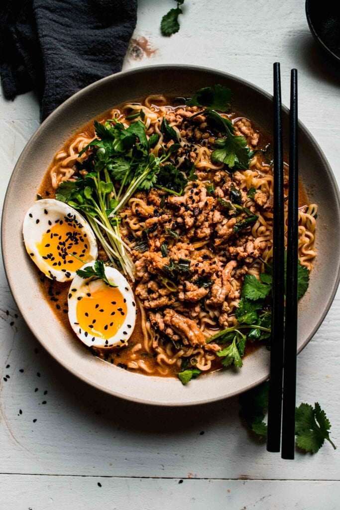 Overhead shot of tan tan noodles in bowl with black chopsticks.