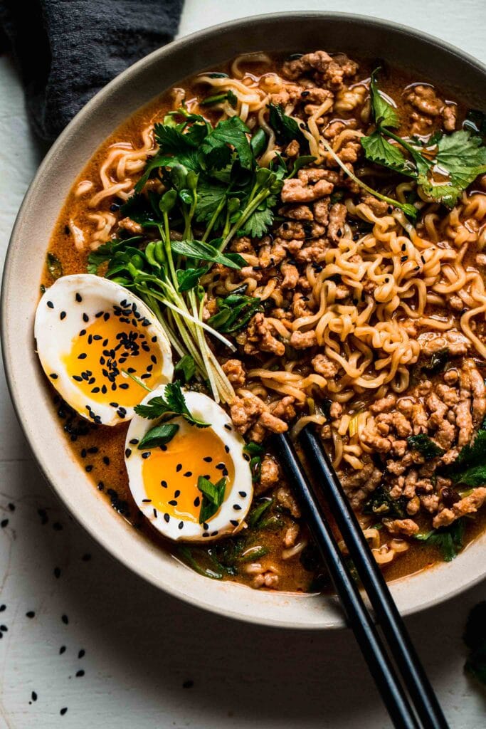 Overhead close up of tan tan ramen in bowl topped with cilantro and egg.