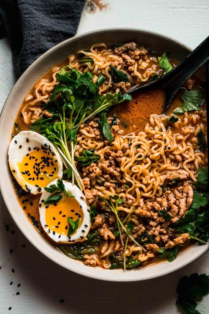 Overhead close up of tan tan ramen in bowl topped with cilantro and egg.
