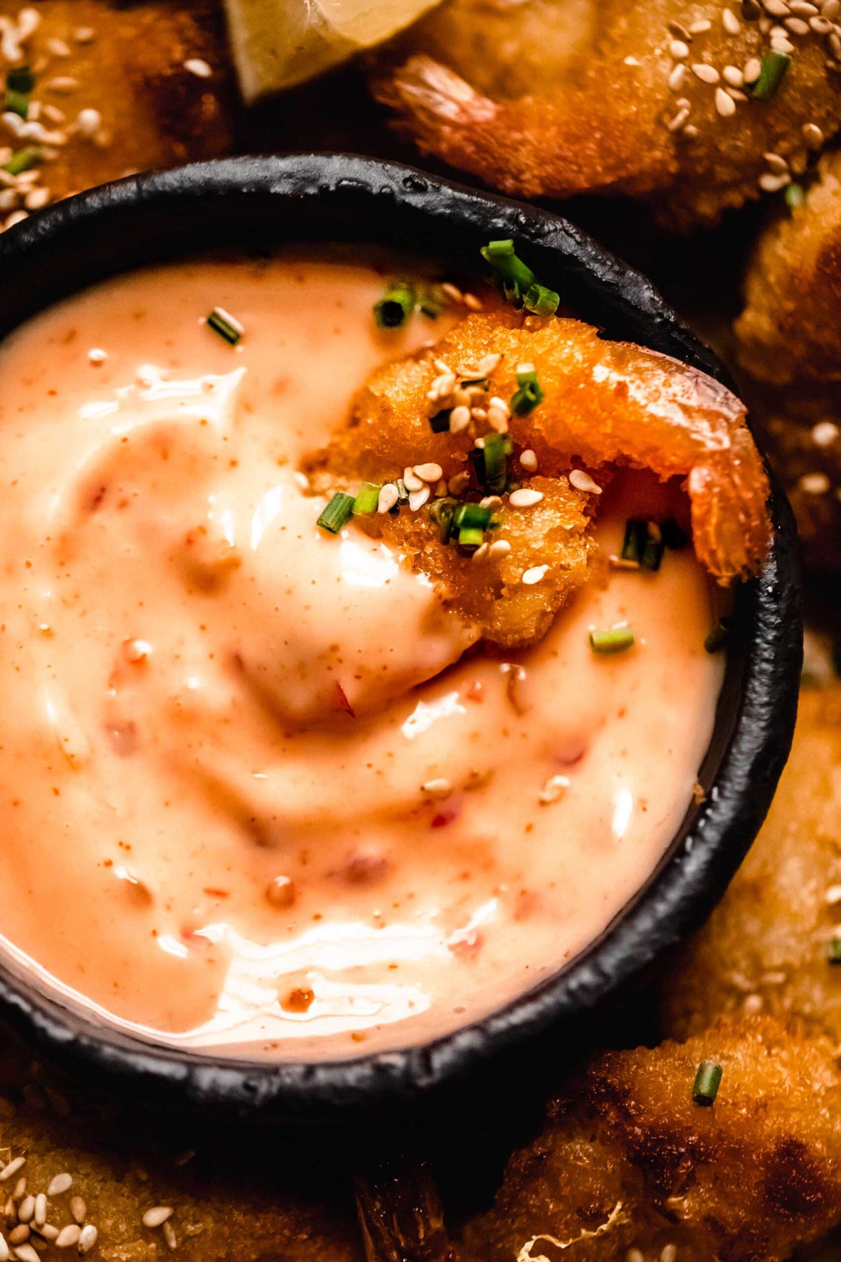 Close up of shrimp dipped into small bowl of bang bang sauce.