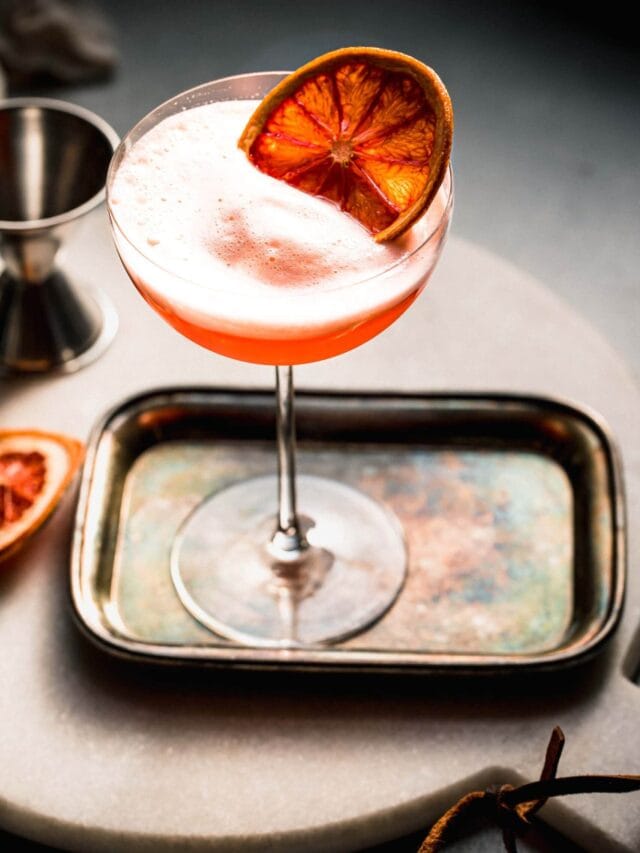 Aperol sour cocktail on small silver tray.
