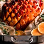 Glazed ham in roasting pan studded with cloves.