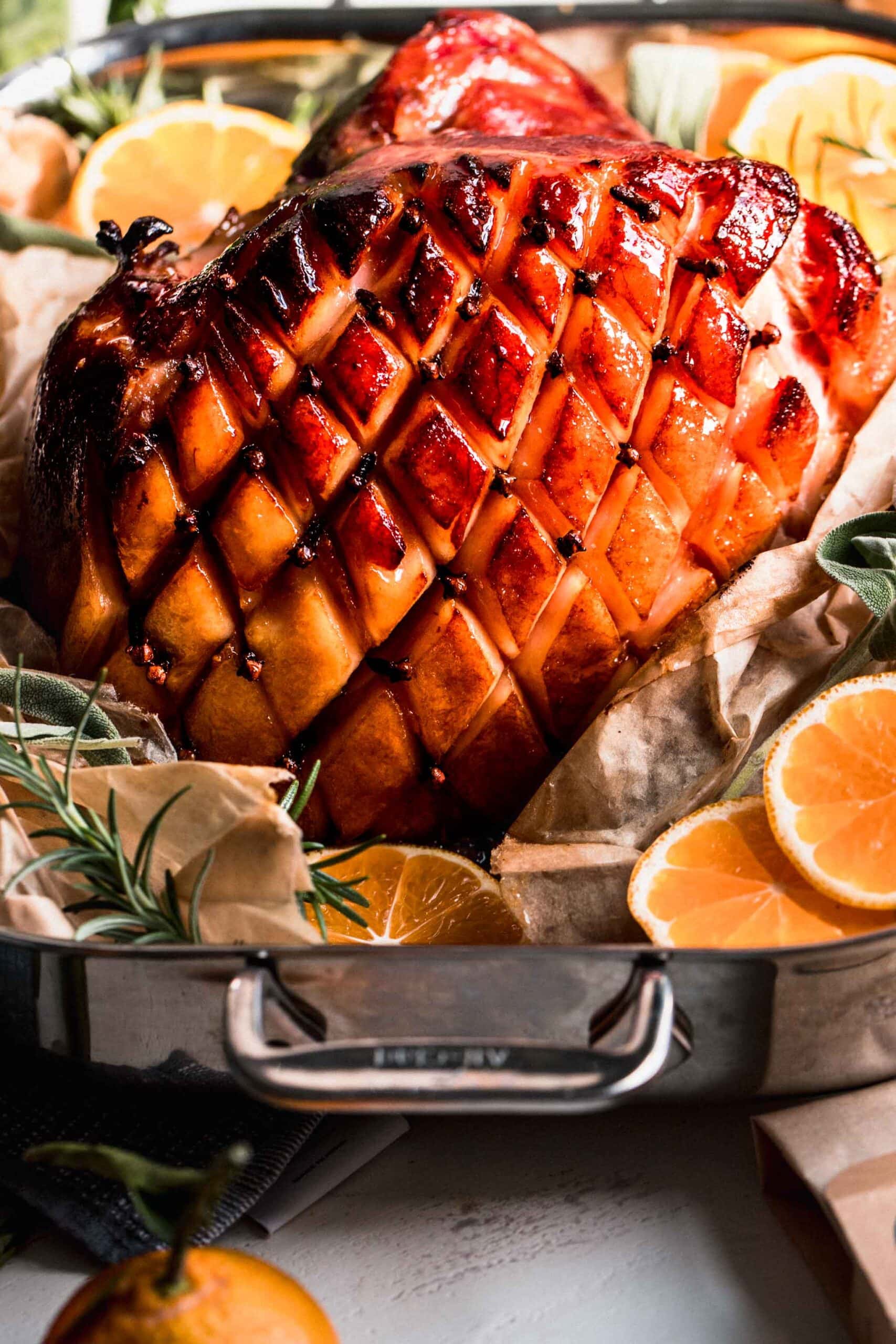 Glazed ham in roasting pan studded with cloves.