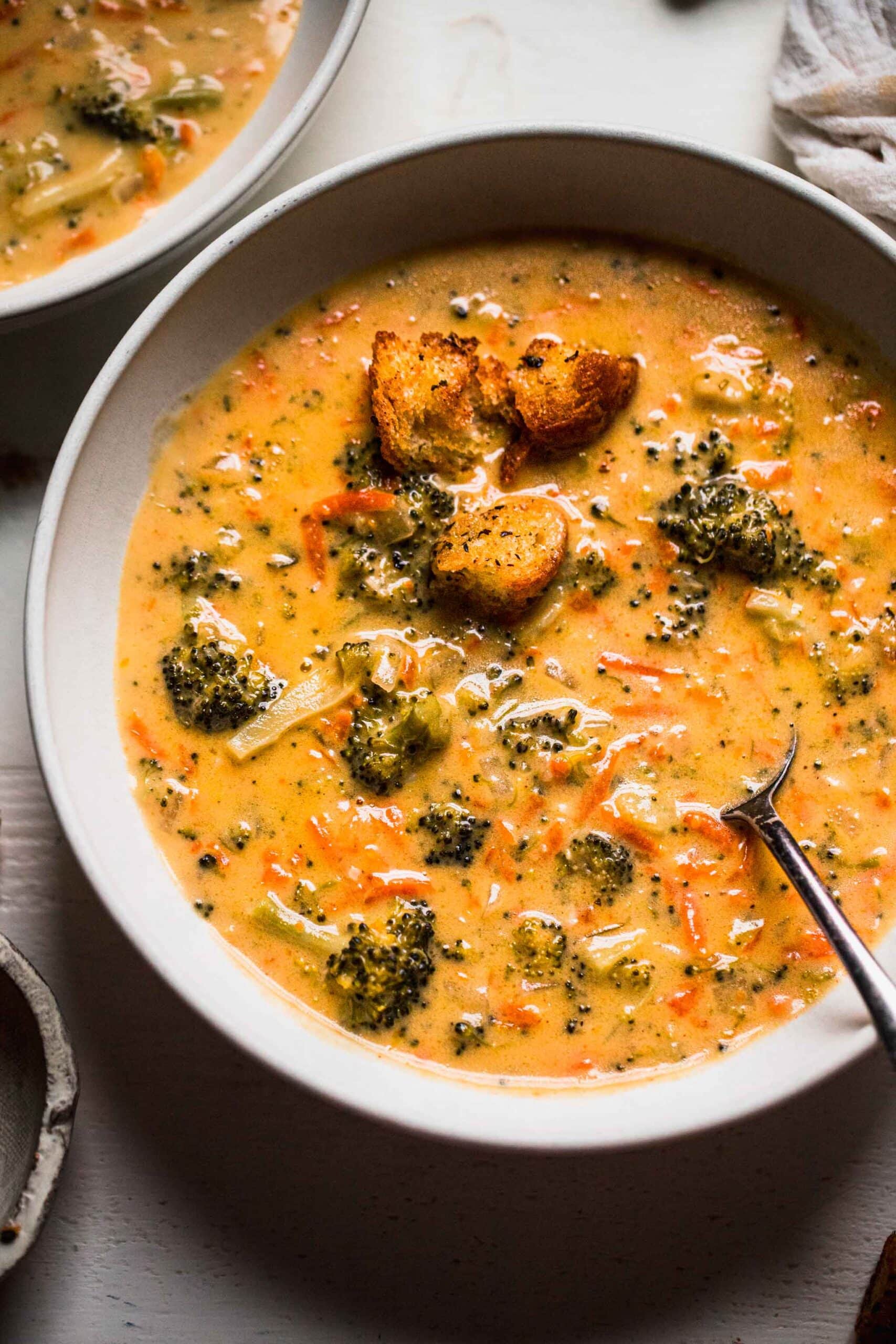 Overhead shot of broccoli cheddar soup in white bowl topped with croutons.