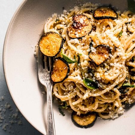 Overhead shot of spaghetti alla nerano in white bowl with fork.