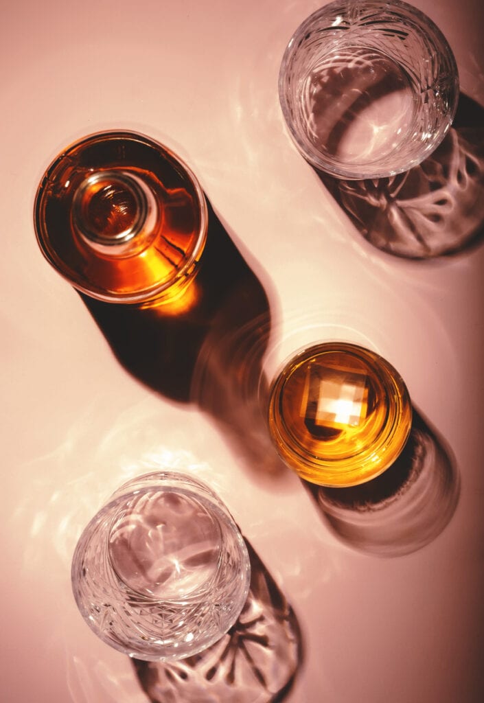 Bourbon bottle on pink background. 