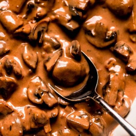 Overhead closeup of creamy mushroom sauce in skillet with spoon.