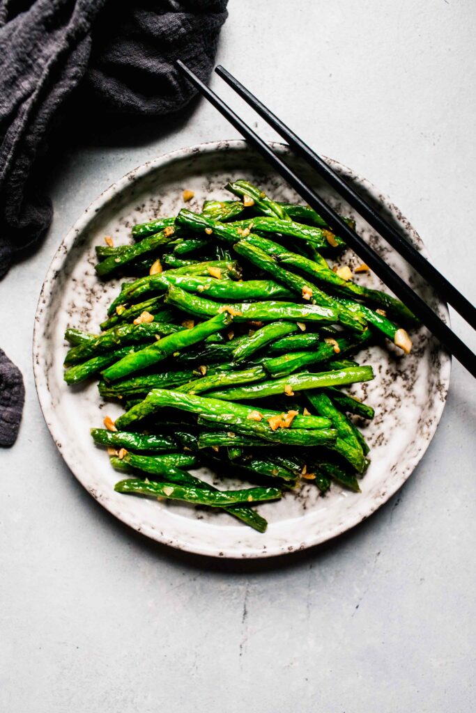 Garlic green beans on plate with chopsticks. 