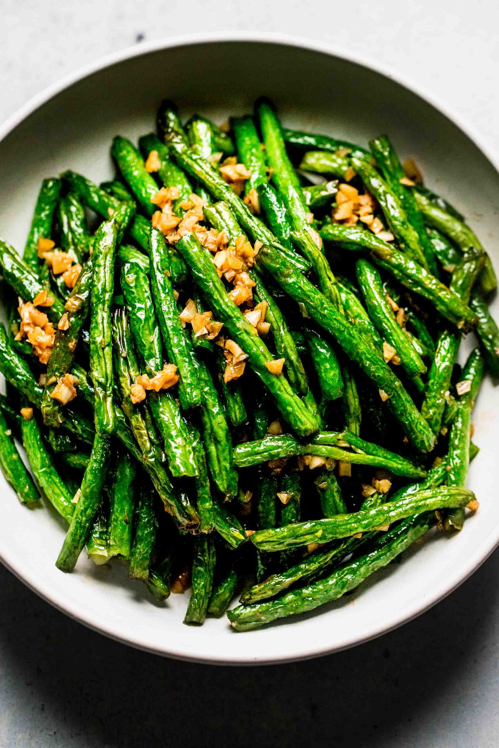 Overhead shot of din tai fung style green beans in white serving bowl.