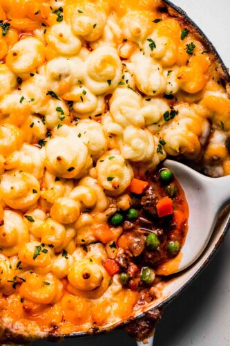Overhead shot of shepherd's pie in skillet with scoop taken out of it.