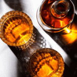 Two glasses of bourbon on counter.