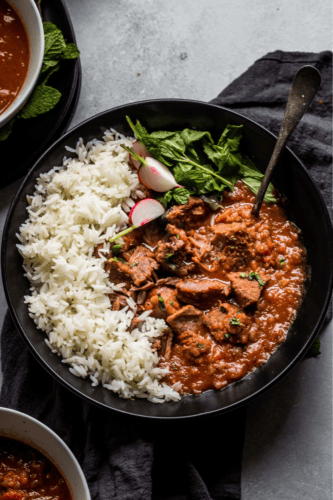 Iranian beef stew in black bowl topped with radishes.