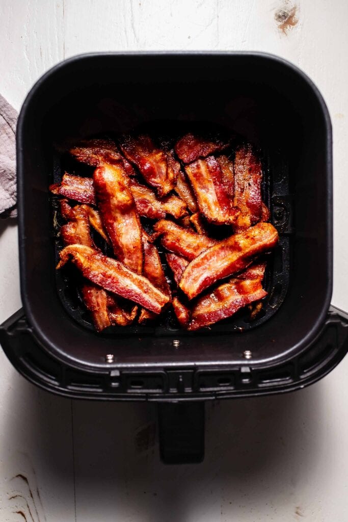 Cooked bacon in air fryer basket. 
