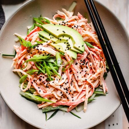 Overhead shot of imitation crab salad in bowl with chopsticks.