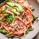 Overhead shot of kani salad in bowl topped with avocado and sesame seeds.