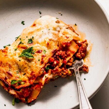 Lasagna in serving dish with fork.