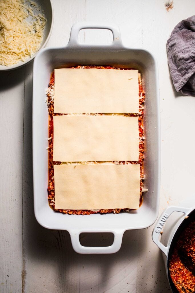 Lasagna noodles being placed into baking dish. 