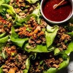 Lettuce Wraps arranged on plate with bowl of sauce.