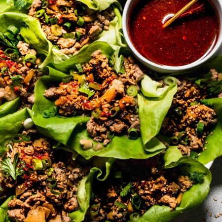 Lettuce Wraps arranged on plate with bowl of sauce.