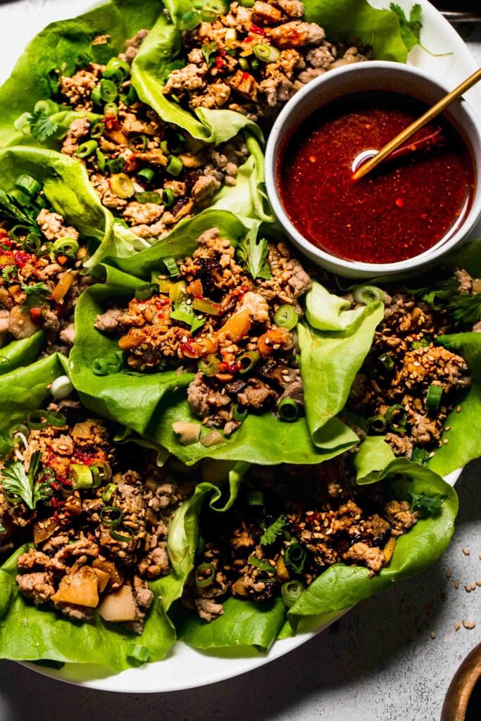 Lettuce Wraps arranged on plate with bowl of sauce.