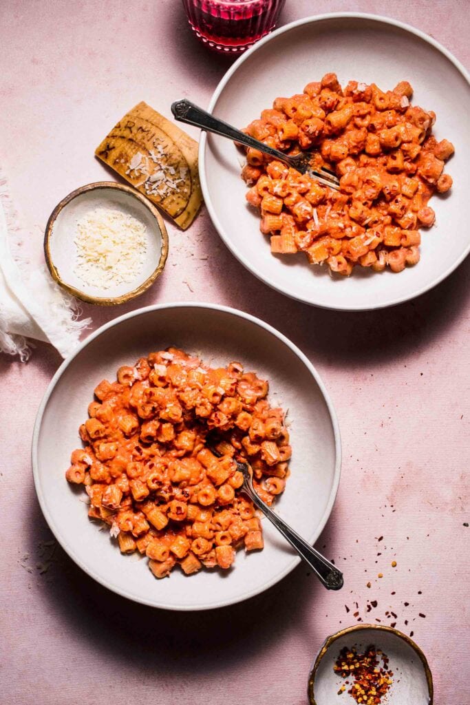 Two bowls of pink sauce pasta on counter. 