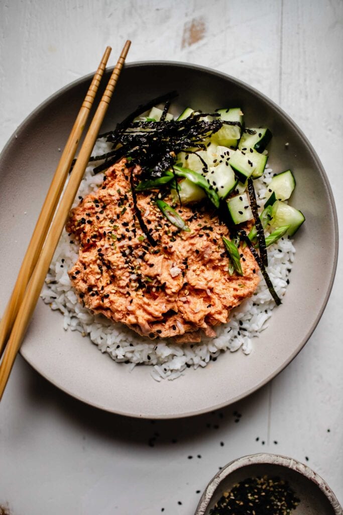 Spicy tuna layered over bowl of rice with nori and cucumbers. 