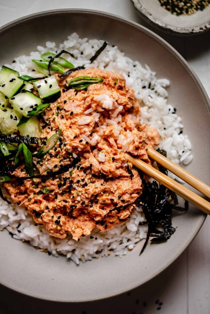 Overhead close up of bowl of spicy tuna rice topped with nori and sesame seeds.