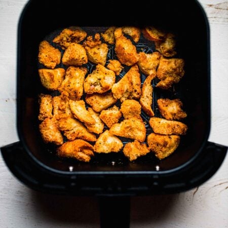 Croutons in air fryer basket.