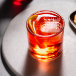 Aperol negroni with large ice cube in glass.