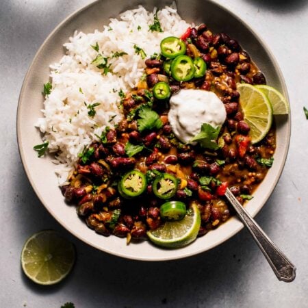 Curry served in bowl with sour cream and lime wedges.