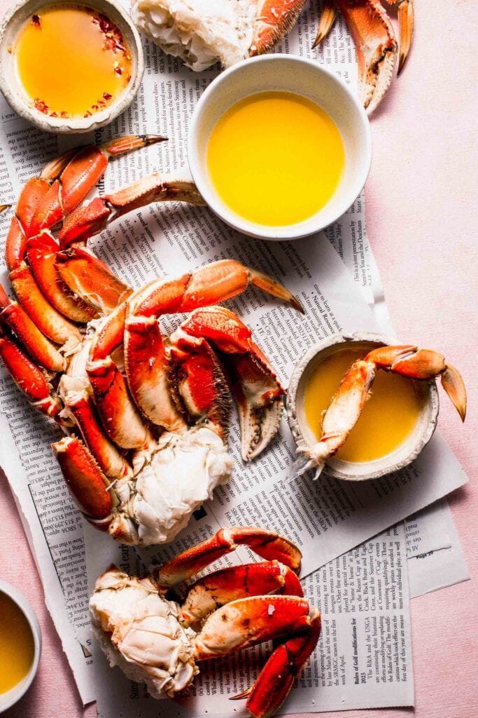 Crabs on newspaper with small bowls of dipping butter.