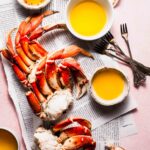 Crabs on newspaper with small bowls of dipping butter.