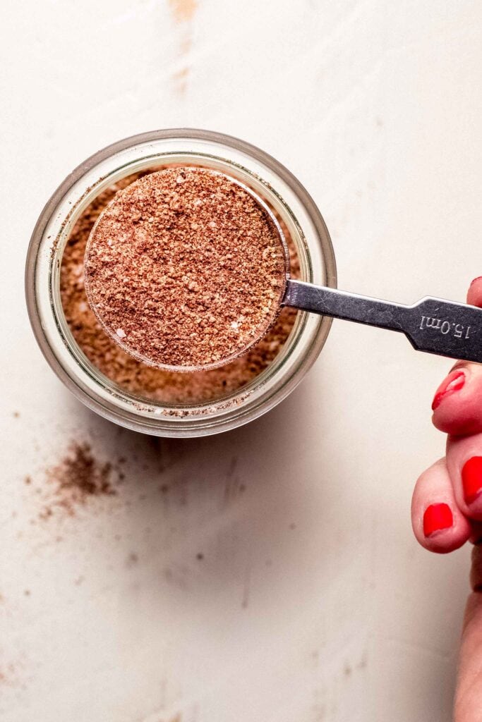 Hand holding spoonful of dry rub for smoked chicken wings. 