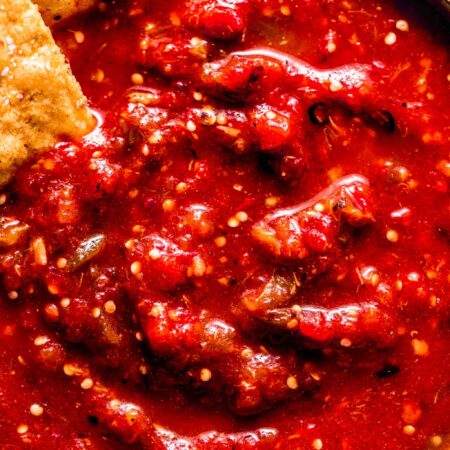 Overhead close up of chipotle hot salsa in bowl with chips dipped into it.