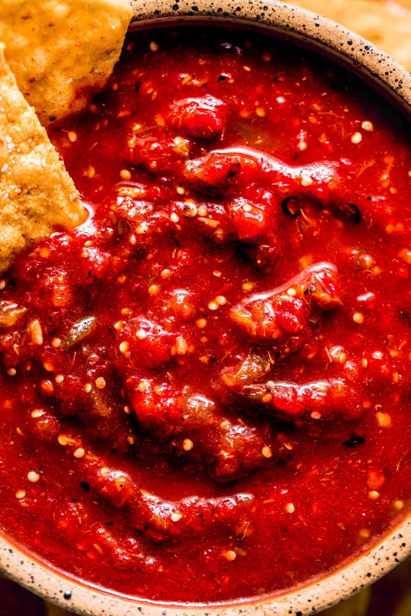 Overhead close up of chipotle hot salsa in bowl with chips dipped into it.