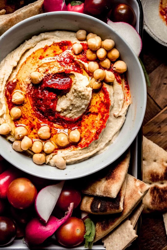 Bowl of hummus topped with chickpeas and harissa. 