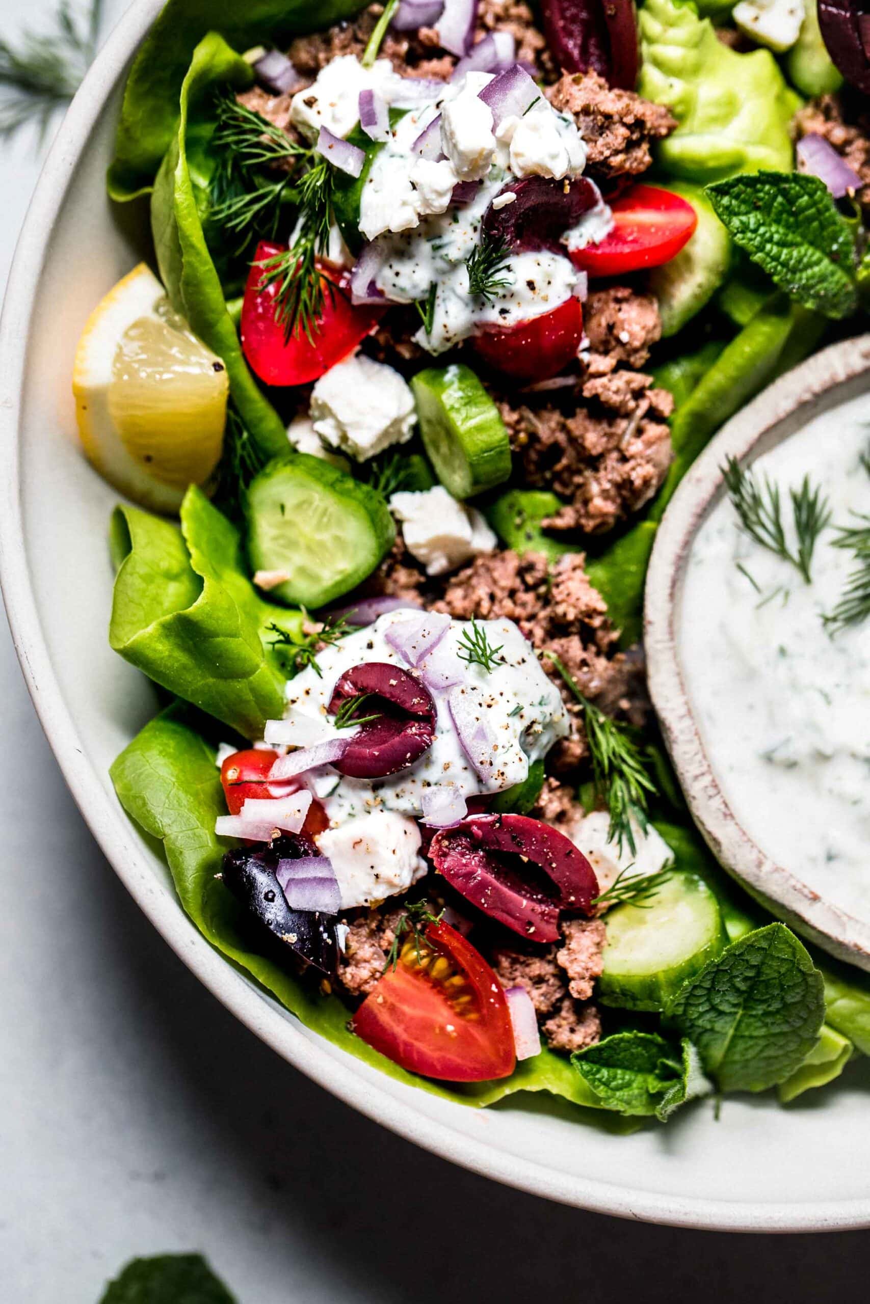 Lamb lettuce wraps arranged in platter with small bowl of tzatziki.