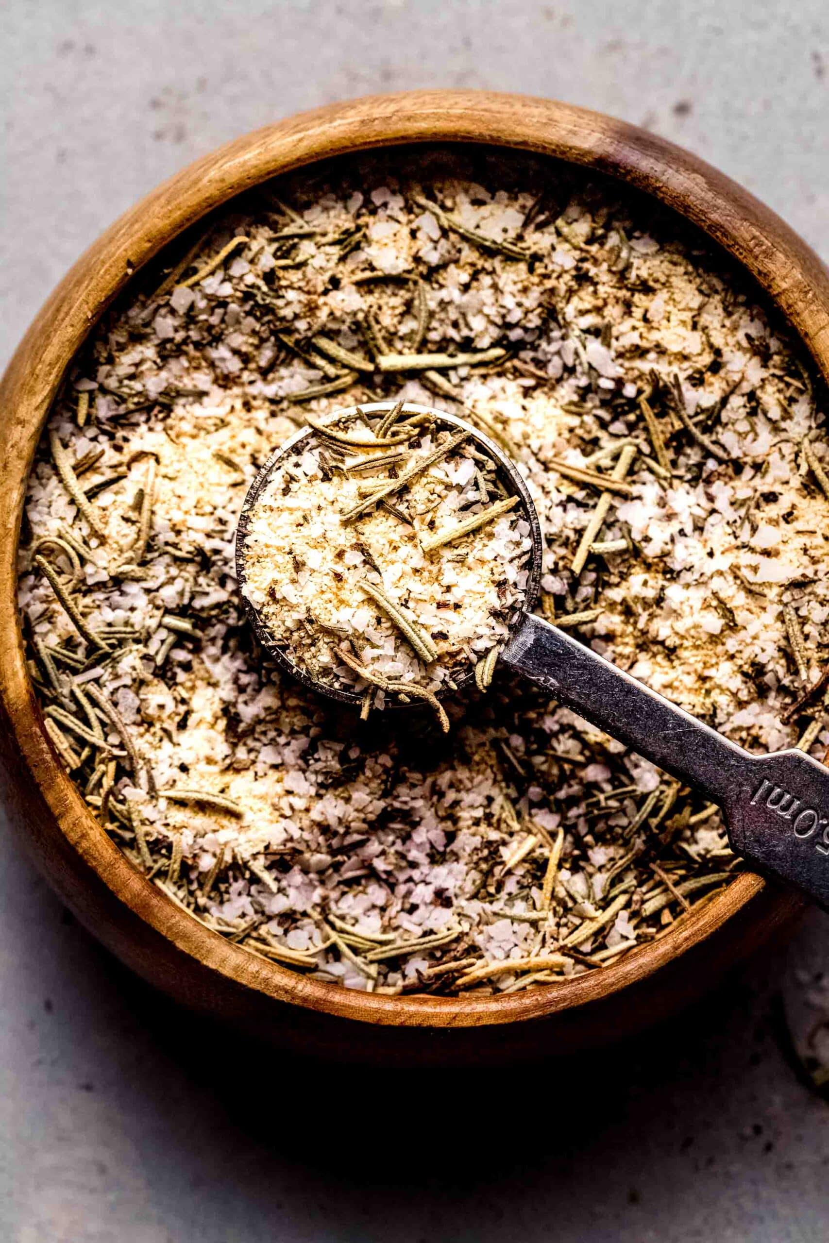 Prime rib rub in small wooden bowl with teaspoon.