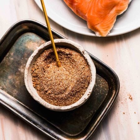 Prepared dry rub in small bowl next to salmon filet.