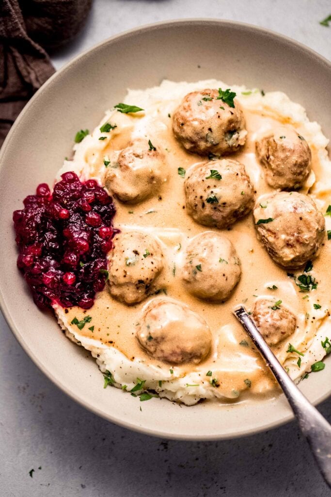Swedish meatballs arranged in bowl with mashed potatoes. 