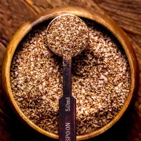 Brisket dry rub in small wooden bowl with teaspoon.