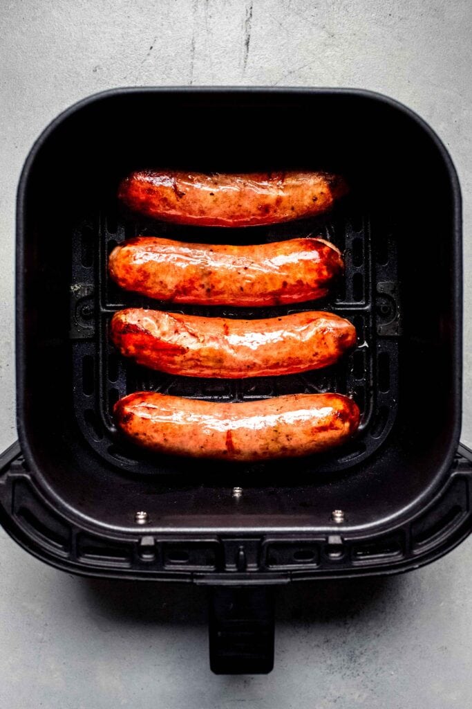 Fully cooked brats in air fryer basket. 