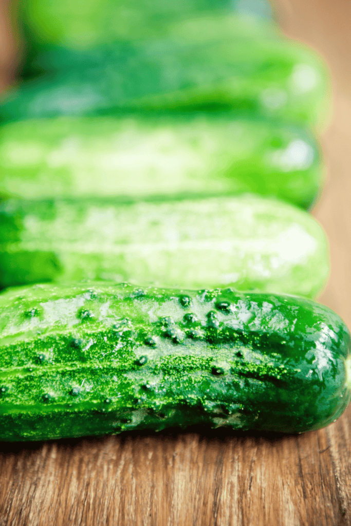 Kirby cucumbers on wooden cutting board.