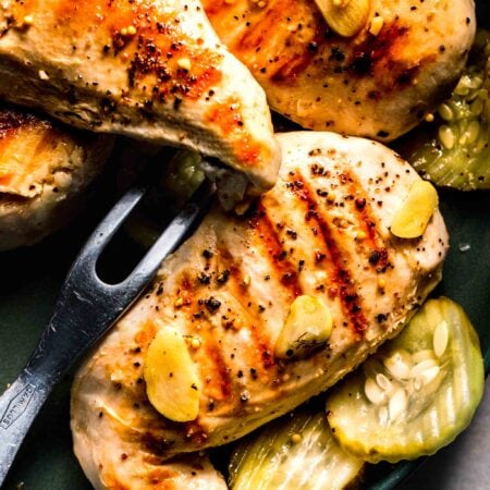 Grilled chicken breast surrounded by pickles.