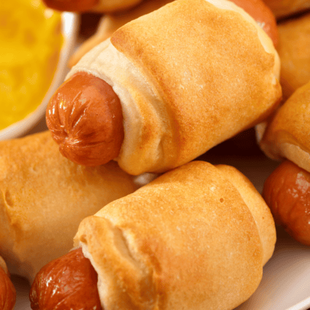 Pile of pigs in a blanket on plate.