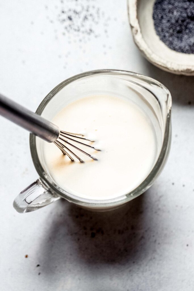 Milk in measuring cup with whisk. 