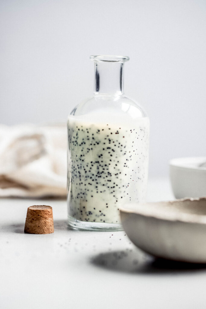 Side view of bottle of poppy seed dressing with cork next to it. 
